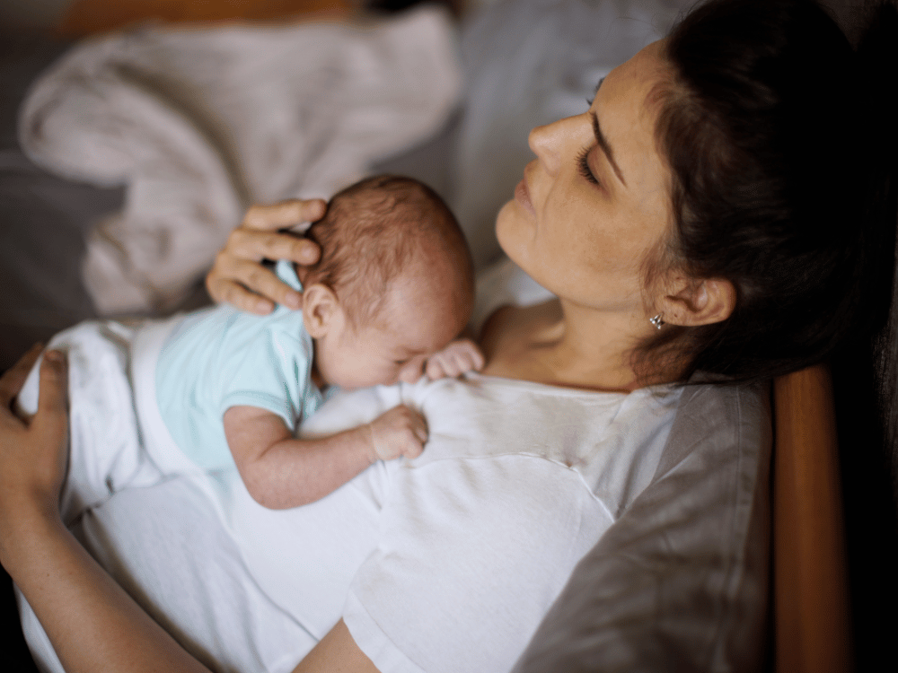 woman holding newborna baby in bed