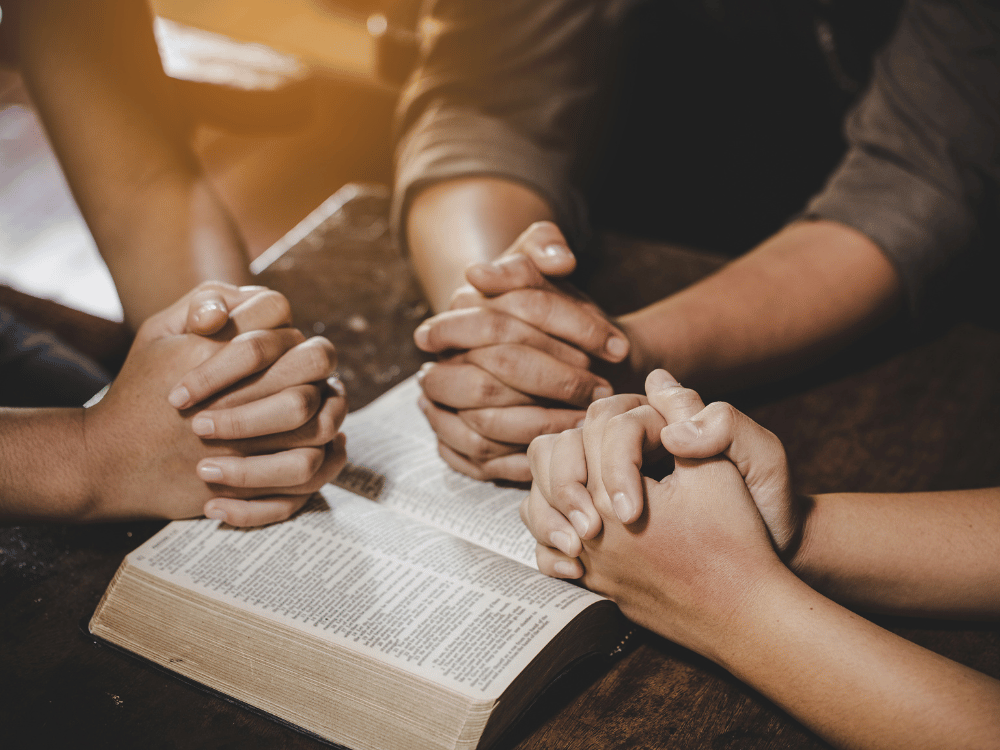 multiple people praying over the bible