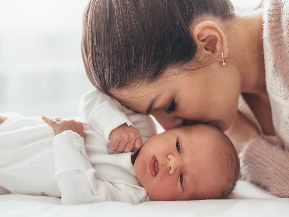 woman kissing newborn baby